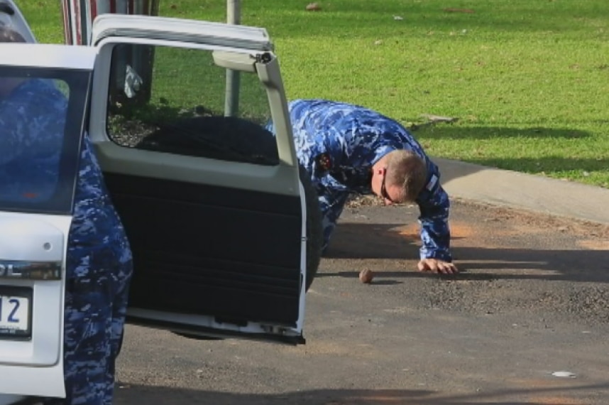 An Army officer leans down to inspect a grenade.