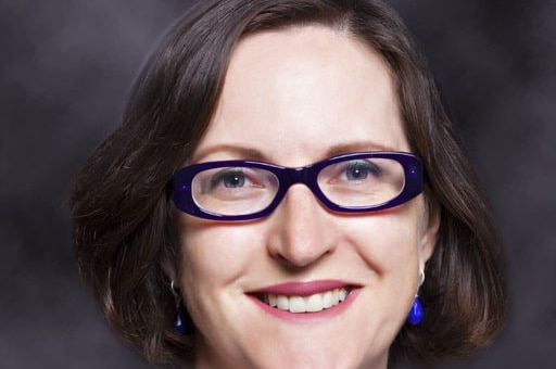 Headshot of a smiling woman wearing glasses.