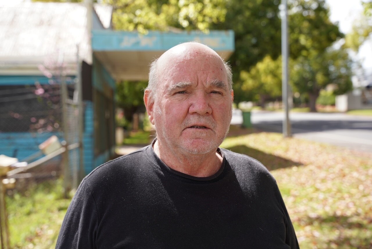 A man in a black t-shirt with a serious look.