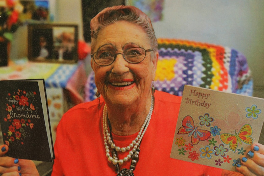 Elderly woman holding up birthday cards.