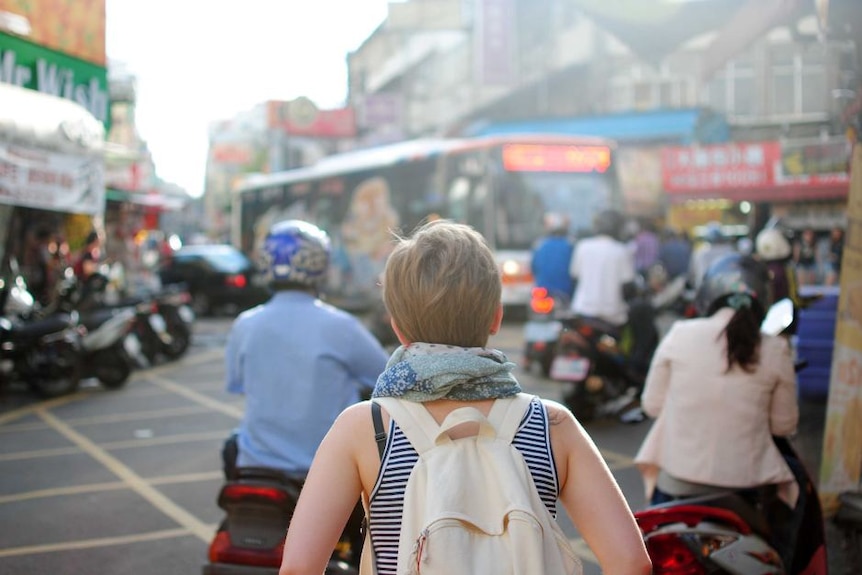 Woman in busy street with backpack