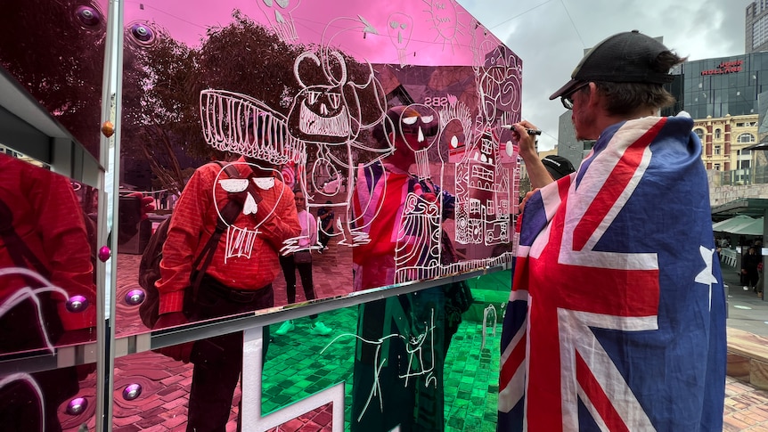 Man wears Australian flag draws on an exhibition in Federation Square Melbourne