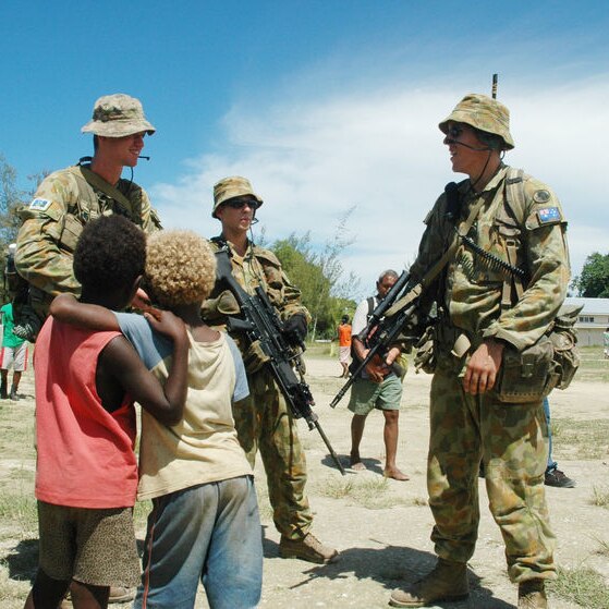 Australian peacekeeping soldiers talk to children in the Solomon Islands.