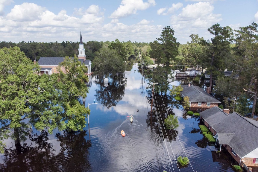 Aerial view of flooded streets as people paddle down the street in kayaks