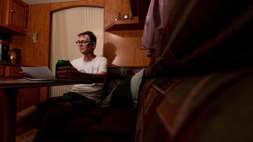 A man sits in a caravan studying papers at his table