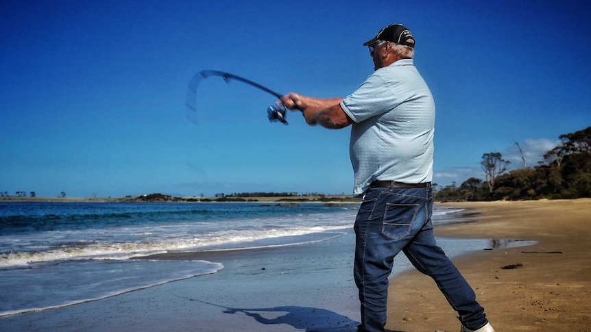 A man with fishing rod at Mayfield Beach, Tasmania, April 2019