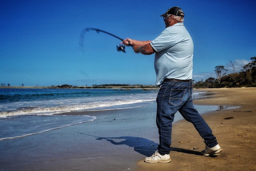 A man with fishing rod at Mayfield Beach, Tasmania, April 2019