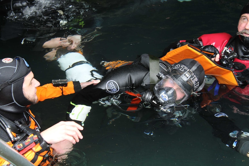 Two divers pull a victim with an imaginary injury out of the water