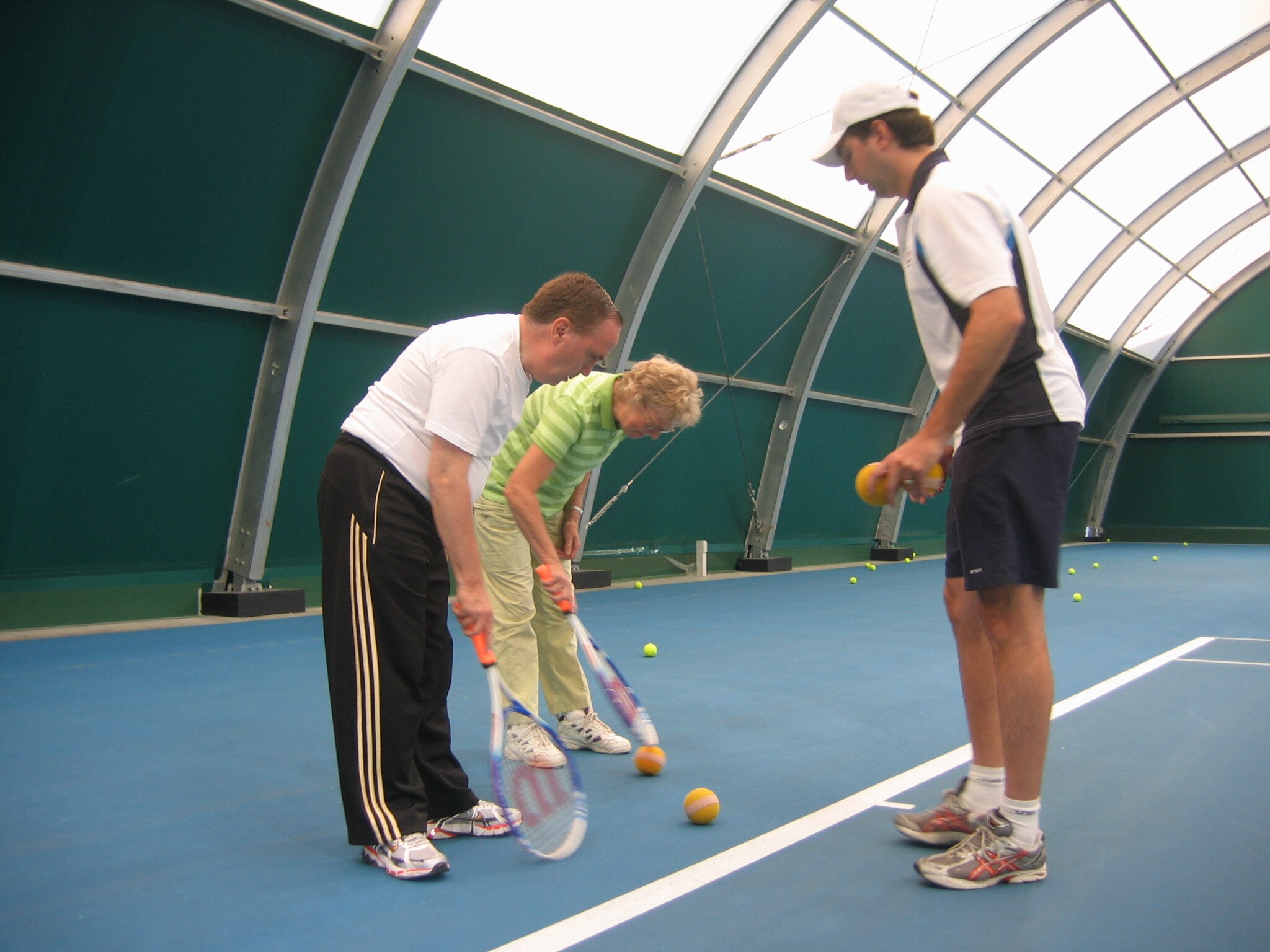Three people standing in a circle playing tennis.
