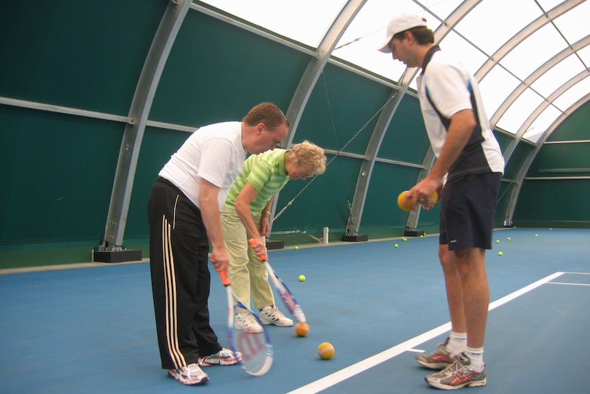 Three people standing in a circle playing tennis.