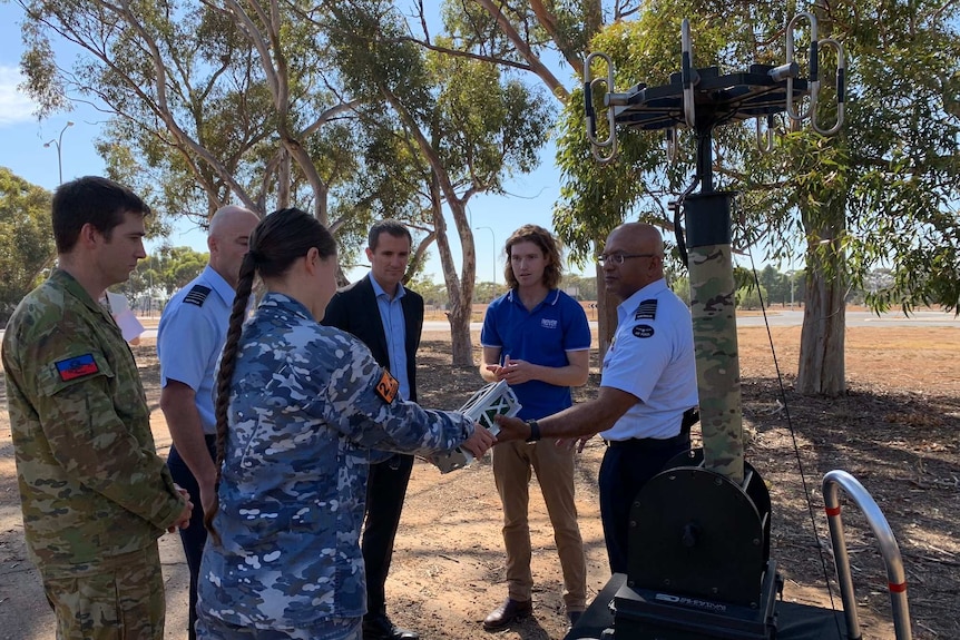 A group of people standing outdoors, discussing South Australia's new mission control centre announcement.