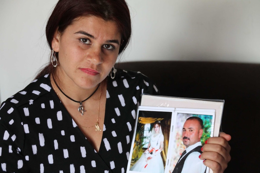 Hayfa Adi holds a photo of herself and her husband Ghazi on their wedding day