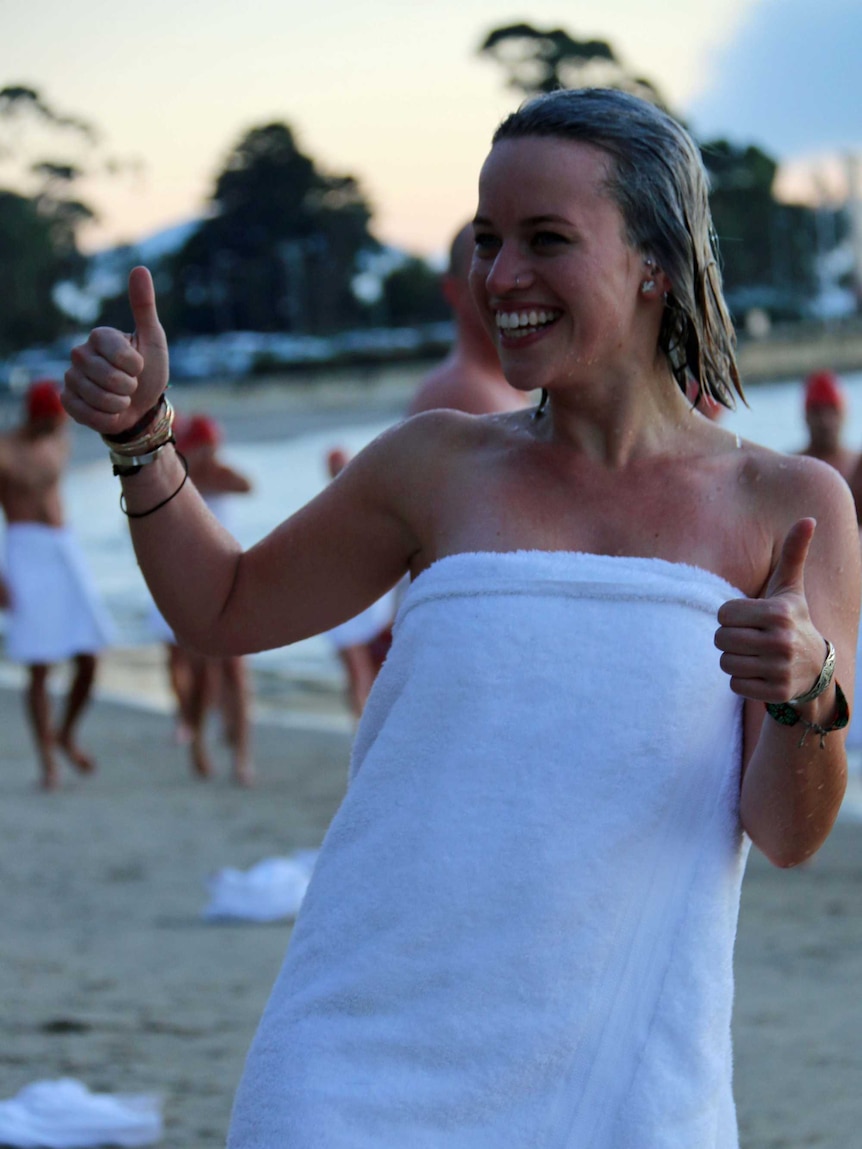 A woman gives the thumbs up after completing the Dark Mofo nude swim in Hobart.