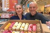 A woman and a man pictured in a patisserie with some of the products