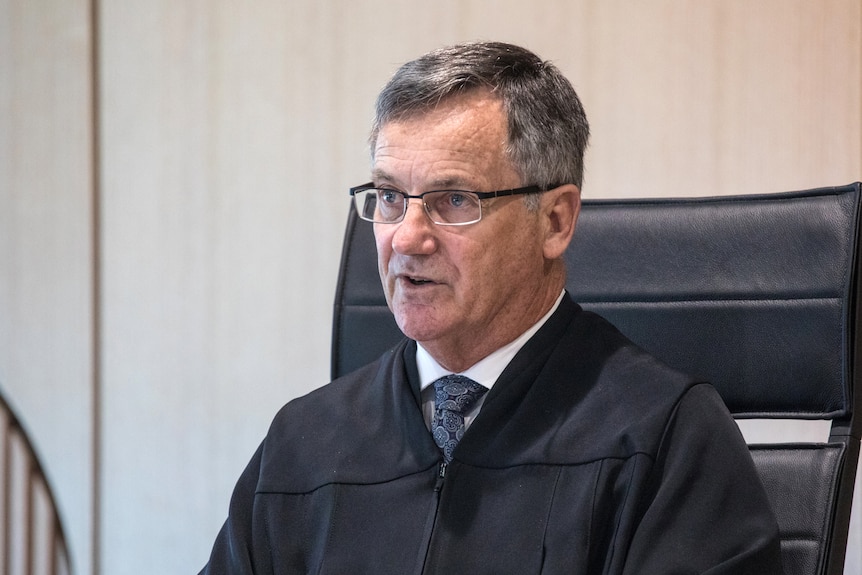 An judge in his robes sitting in a courtroom