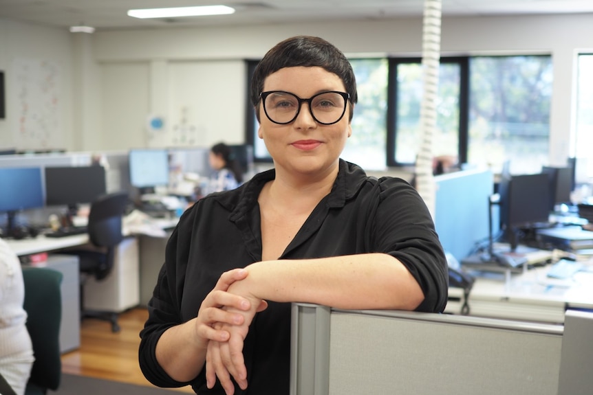 A woman stands in an office.