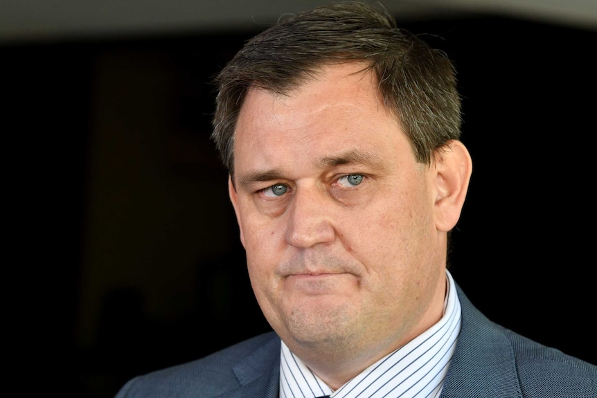 A close-up of a stern-looking man wearing a suit.