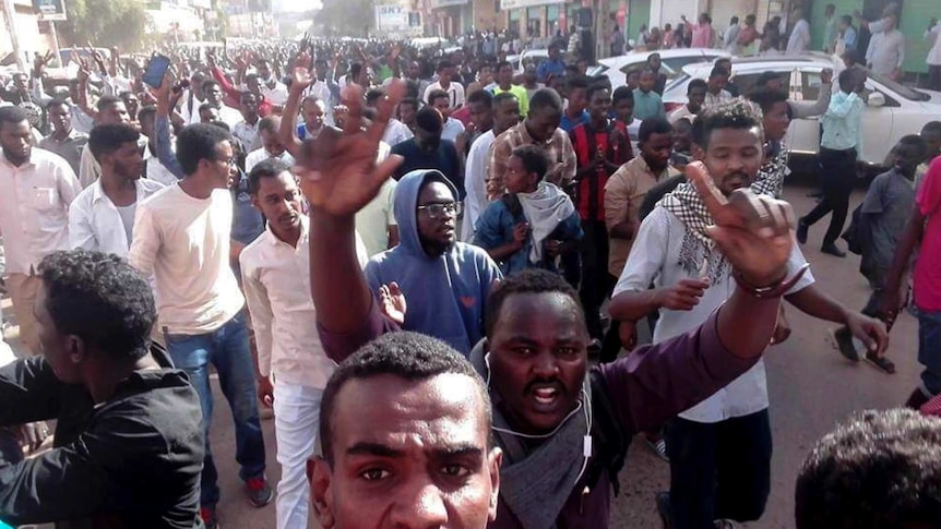 A group of sizeable group of men march down a Khartroum street amid widescale protests.