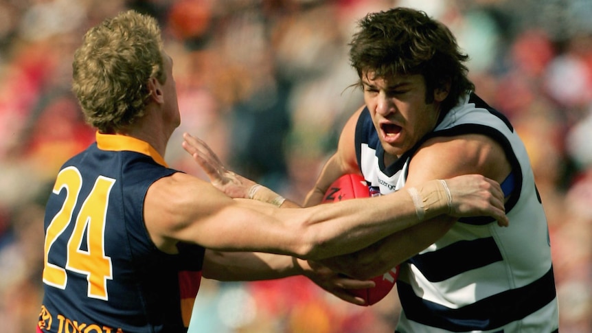 A player tries to evade a defender during an Aussie Rules match