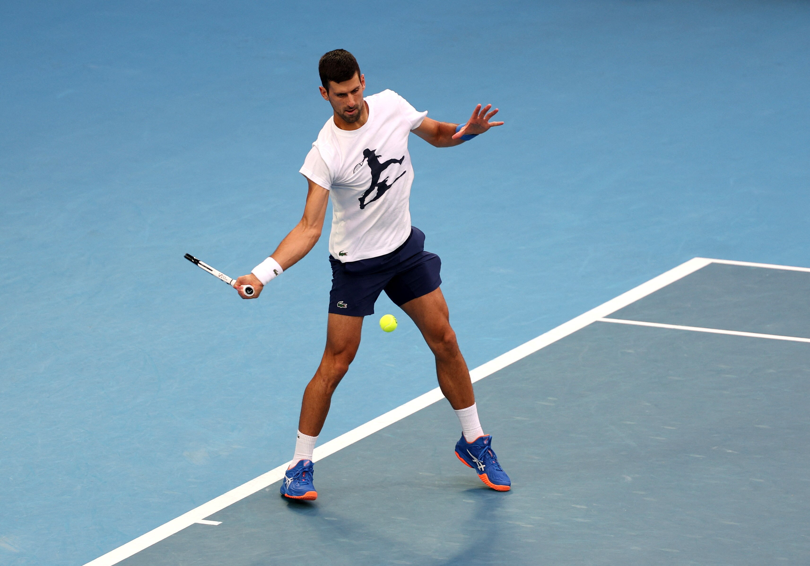 A man hits a forehand on a tennis court.