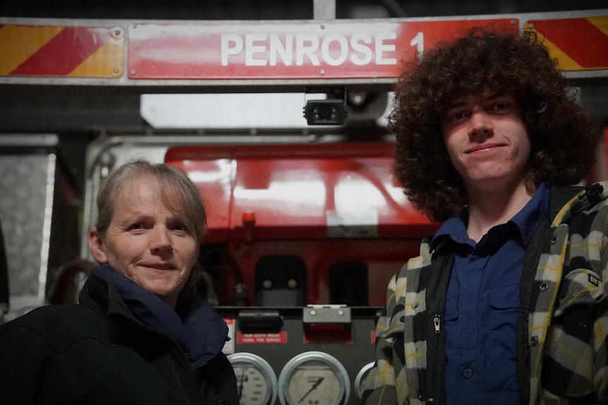 A woman and a teenager stand together in front of a firetruck that has Penrose written on it.