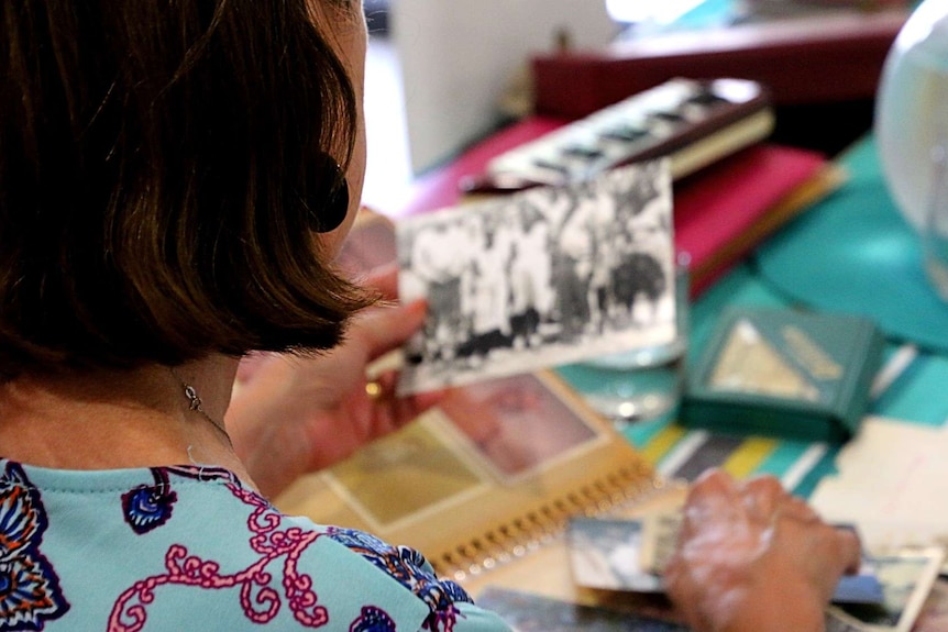 An over shoulder shot of a woman seated at a table looking over old photos