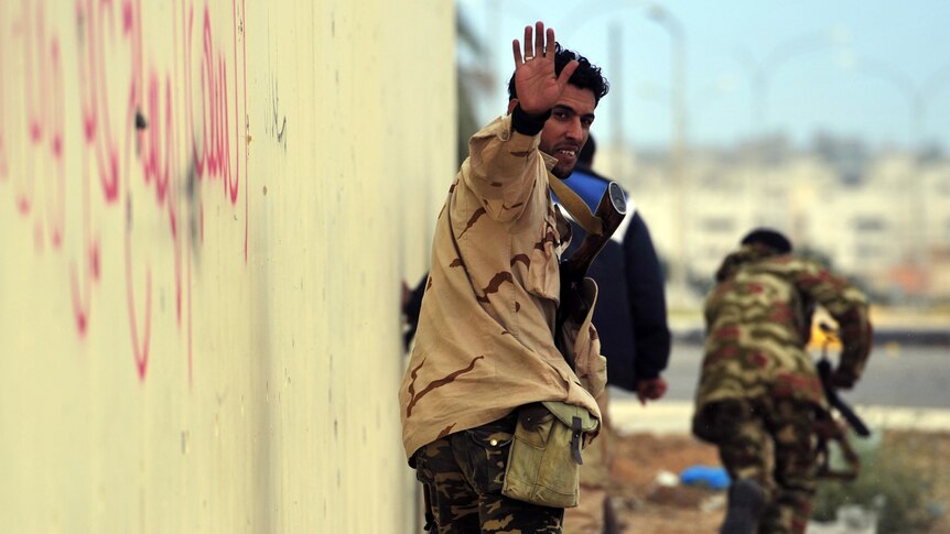 A National Transitional Council fighter takes positions during a shoot-out with troops loyal to Gaddafi in Sirte.