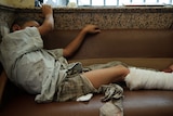 Boy lies on couch in Syrian hospital