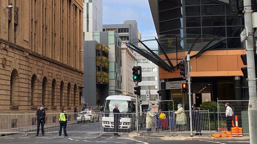 A hotel and a bus and people wearing PPE