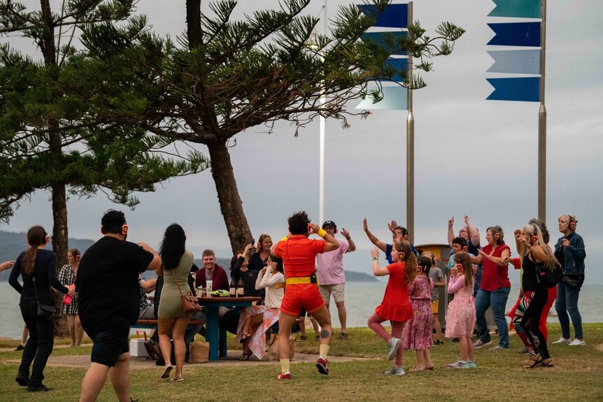 A group of dancers surround a table of people on the Strand in Townsville