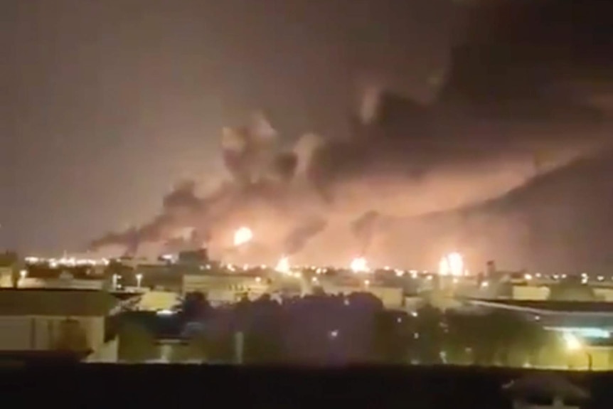 Smoke and fire is seen rising from a factory at night time.