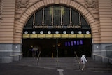 A man walks past the entrance to Flinders Street Station which is completely empty.