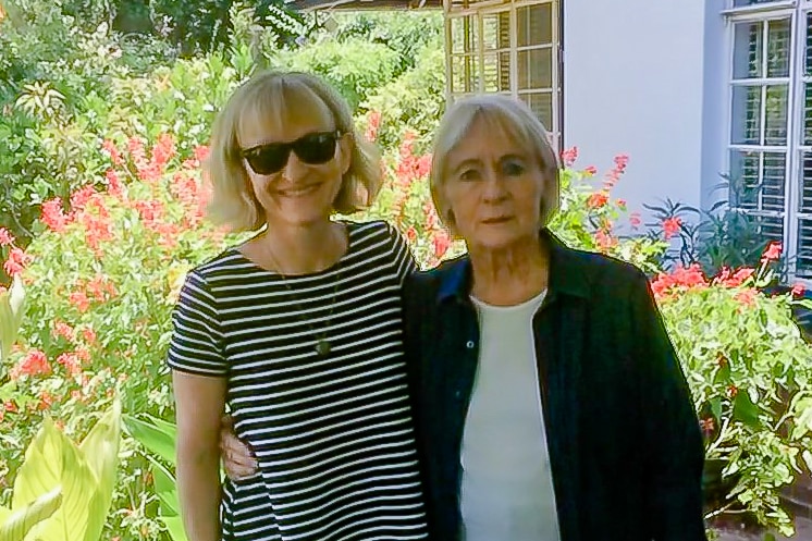 A picture of a woman with blonde hair and sunglasses standing next to her mother with grey hair.,