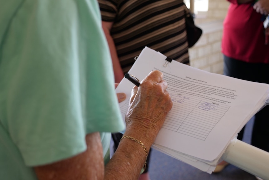 Picture of elderly lady signing a petition.