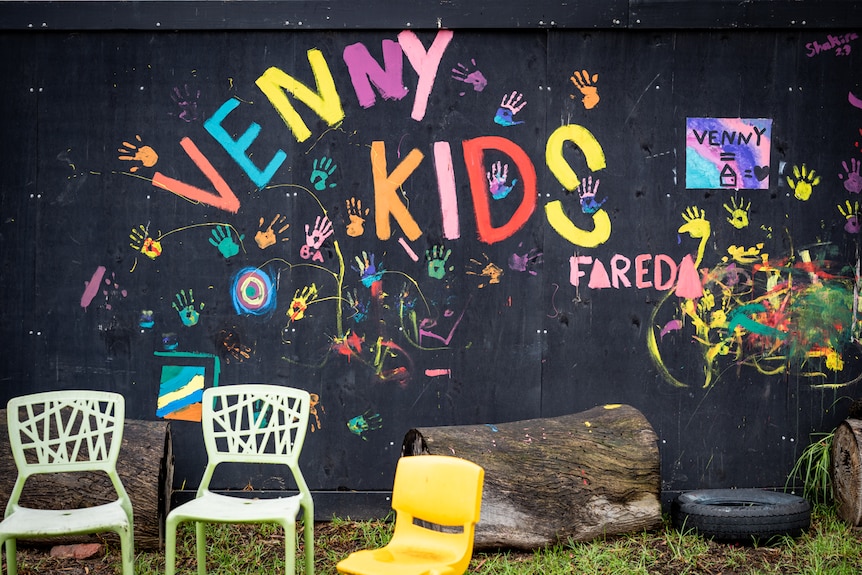 A giant blackboard is seen with the phrase 'Venny kids' scrawled onto it