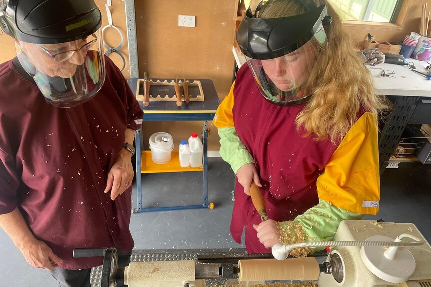 Two ladies doing woodwork with helmets on