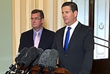 Lawrence Springborg speaks at a podium as John McVeigh stands next to him.