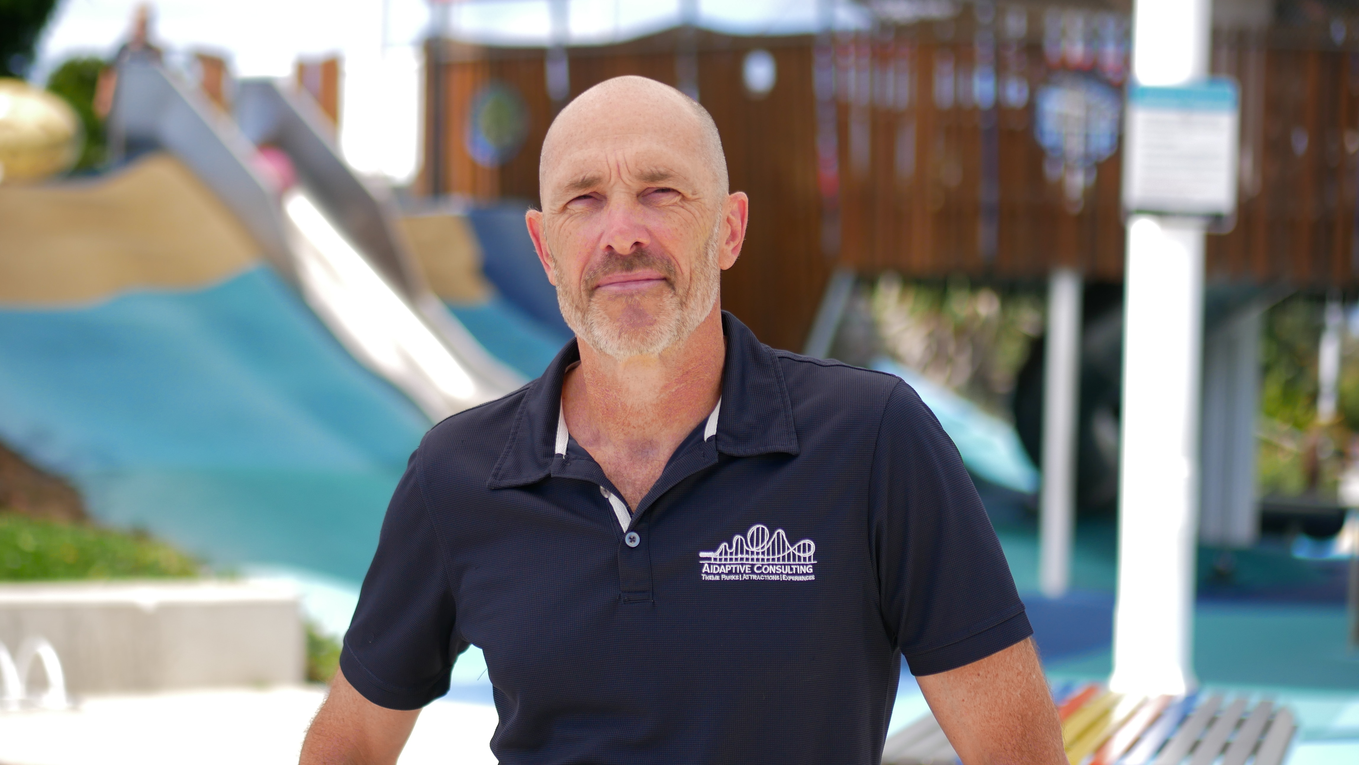 A man in a blue polo looks seriously at the camera