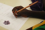 Indigenous student hand holding pencil generic image.