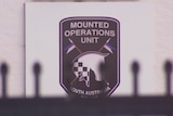 A sign reading 'Mounted Operations Unit South Australia Police' with the shadow of a fence in front of it