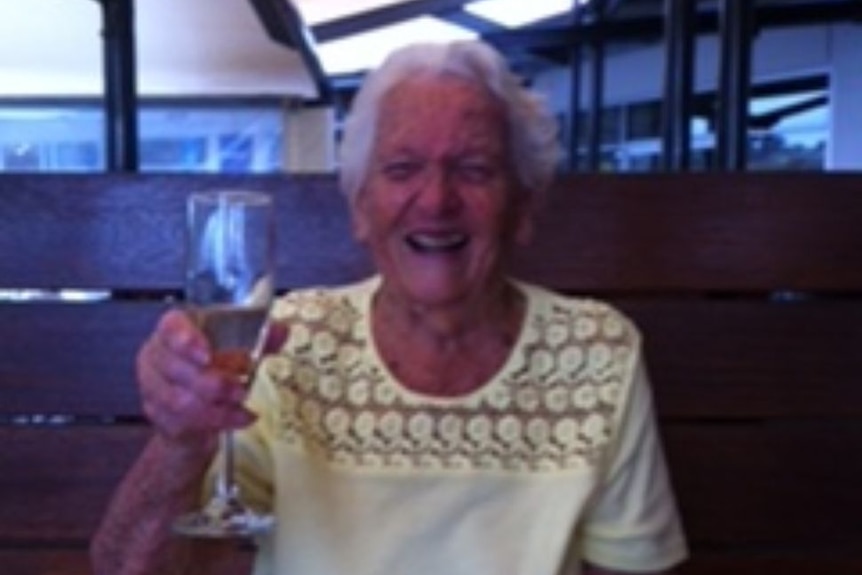 Mid shot of elderly woman with a glass of alcohol in her hand