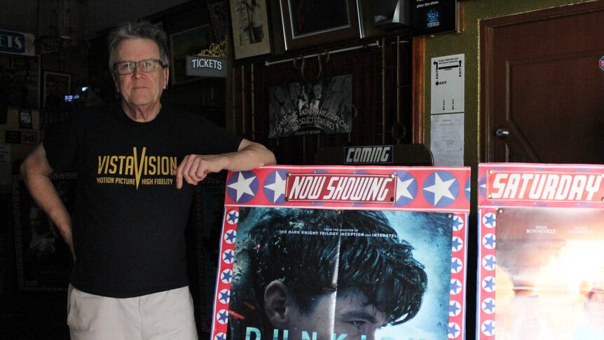 David McGowen standing with Dunkirk film sign at the Plaza Theatre.