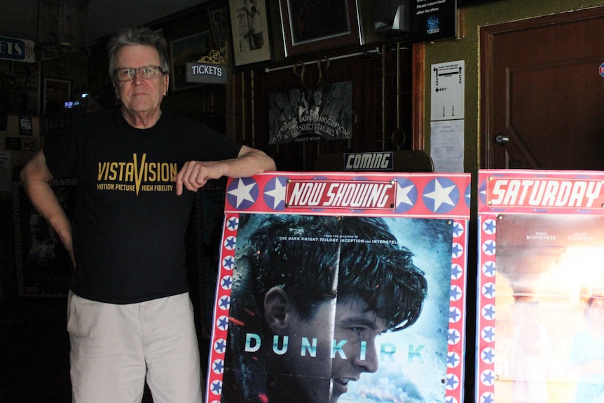 David McGowen standing with Dunkirk film sign at the Plaza Theatre.