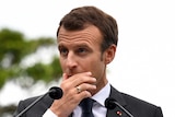 President of France Emmanuel Macron has his hand over his mouth during a press conference.