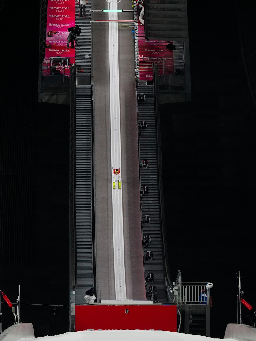 Robert Johansson of Norway can seen travelling down a hill at night in the winter olympics ski jumping