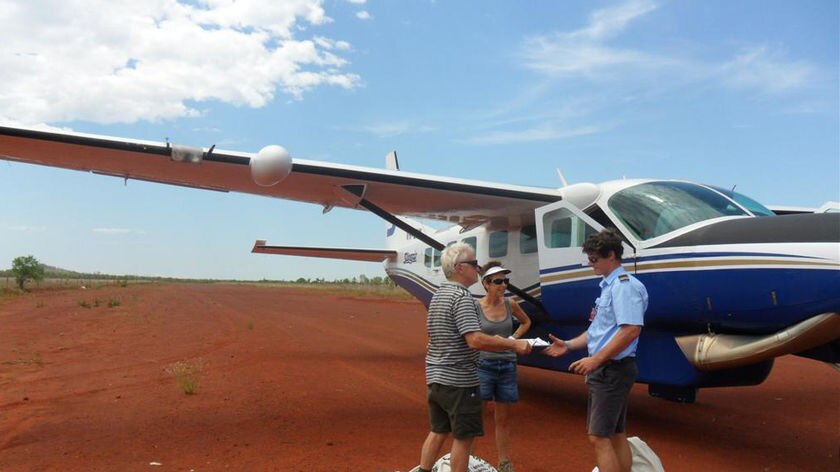 Pilot Greg Niven hands mail to Linda and Max Jones who are travelling around Australia