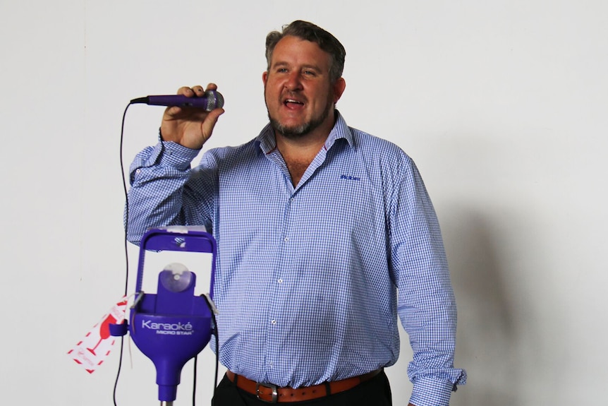 Pickles operations manager Rhys Jones sings into a microphone of a karaoke machine that was left at Brisbane airport.