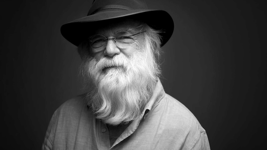 a black and white image of david olney wearing glasses and a wide-brimmed hat and a long beard