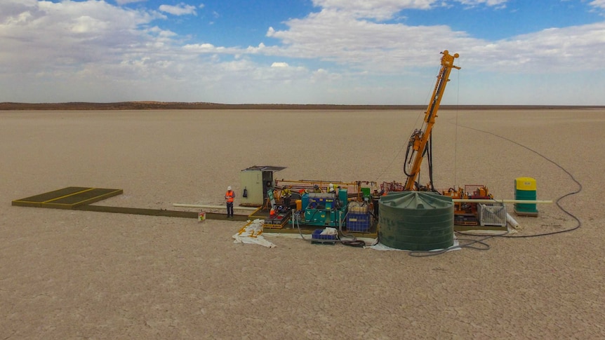 a small drilling platform sits in the middle of a white expanse.  The sky is blue and a man stands on the platform