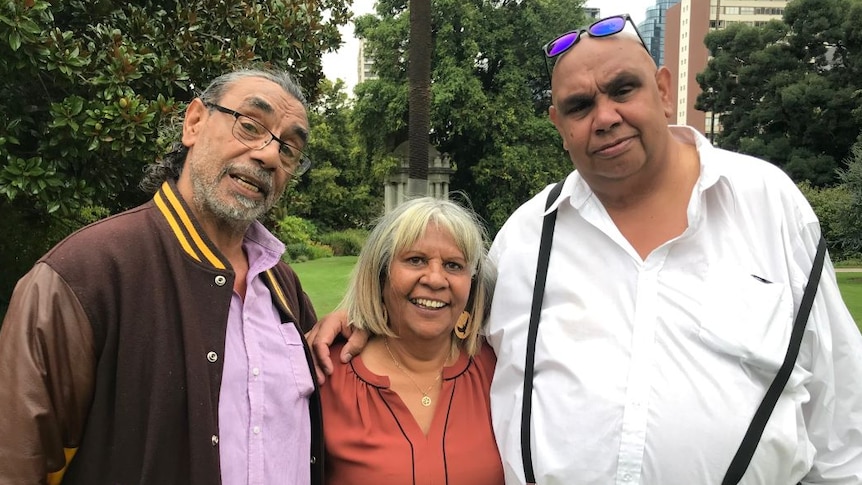 The Edwards siblings stand in a park with their arms around each other.